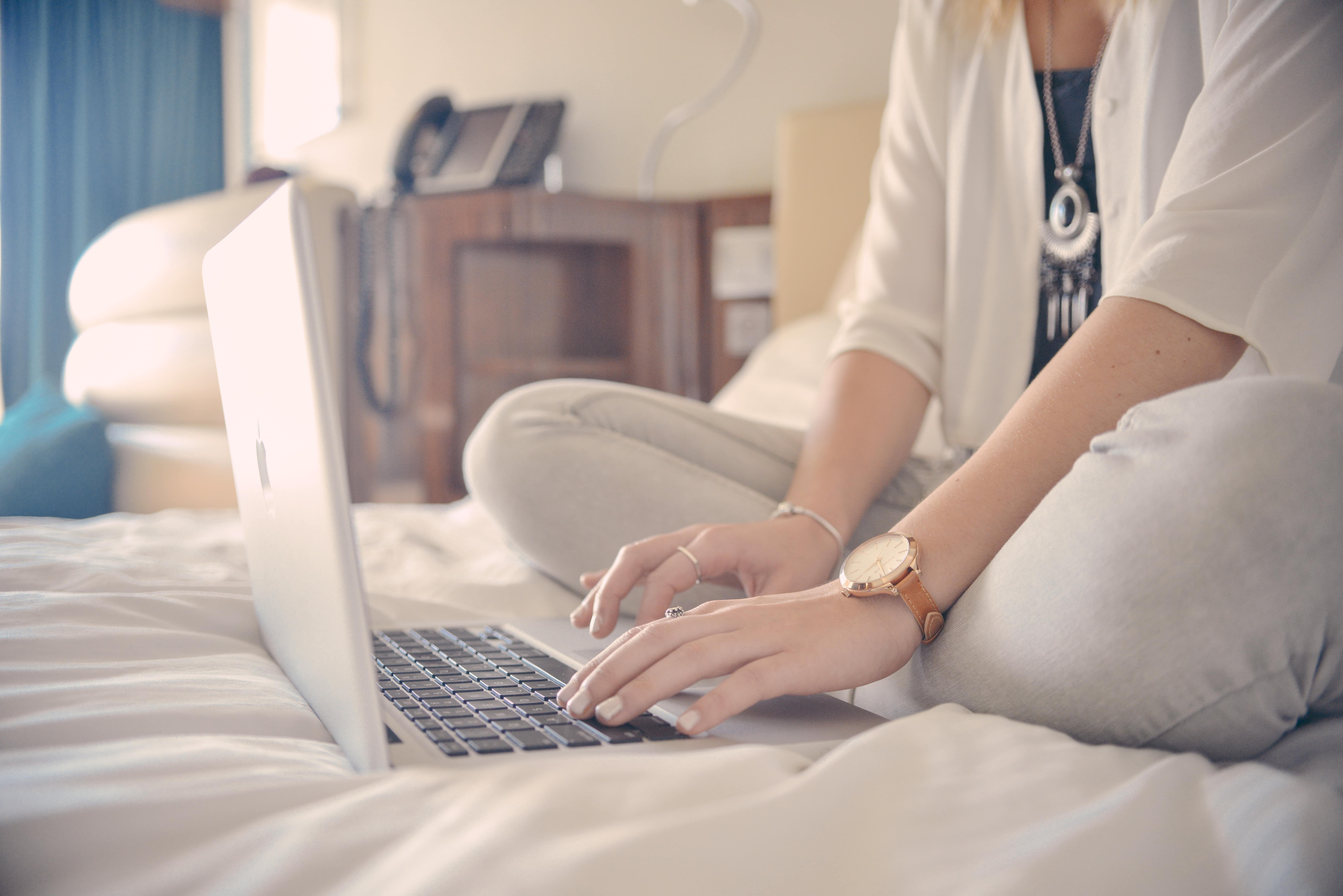 Woman sitting on a bed working on her laptop