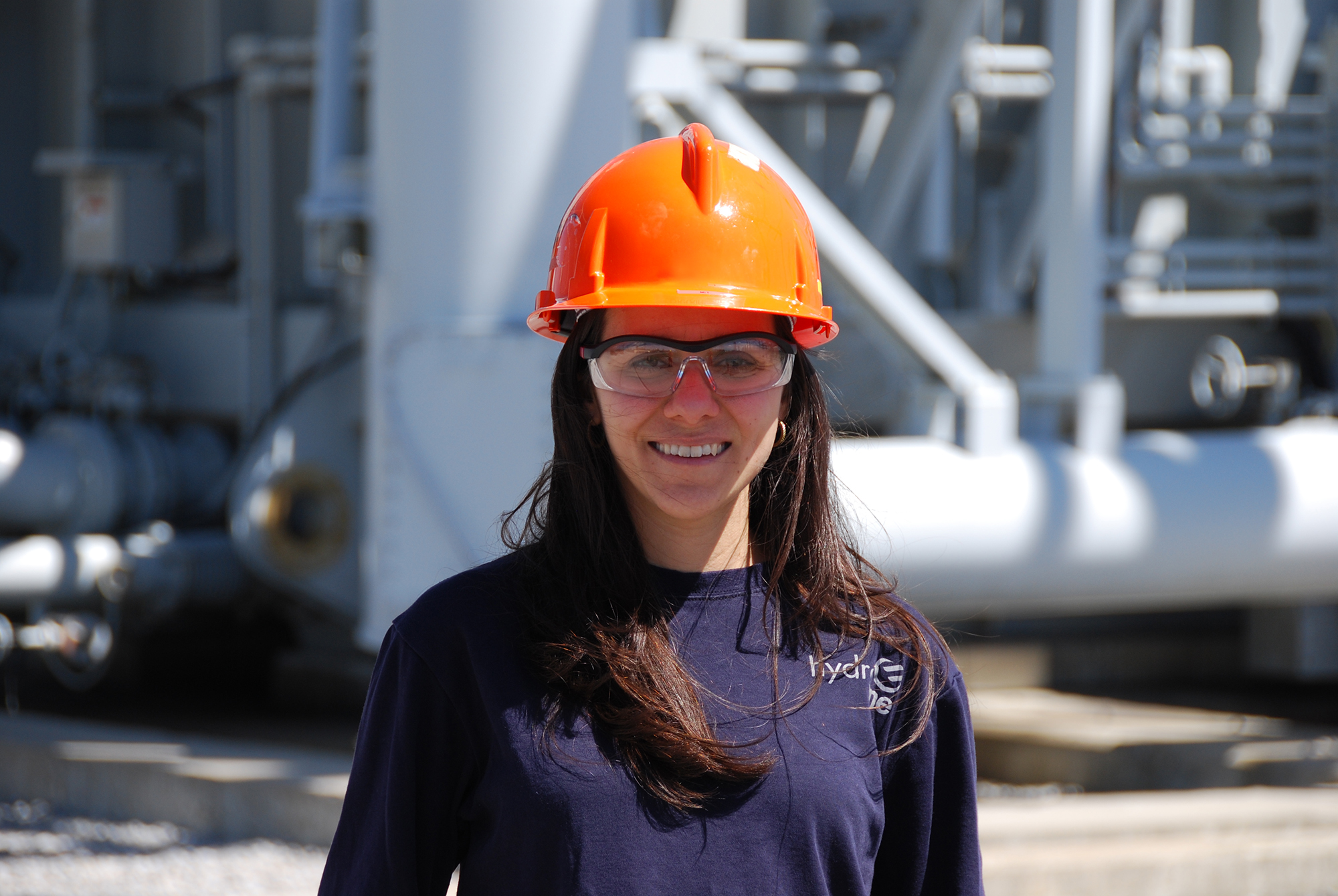 photo of a female Hydro One engineer wearing a hard hat inside a large transmission station
